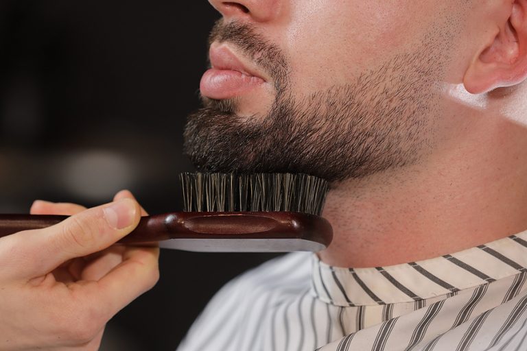 Haircut Head And Beard In A Barbershop. Barber Puts On And Combs
